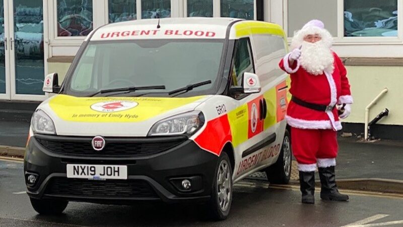 Santa Claus stands next to a Bloodrun van.