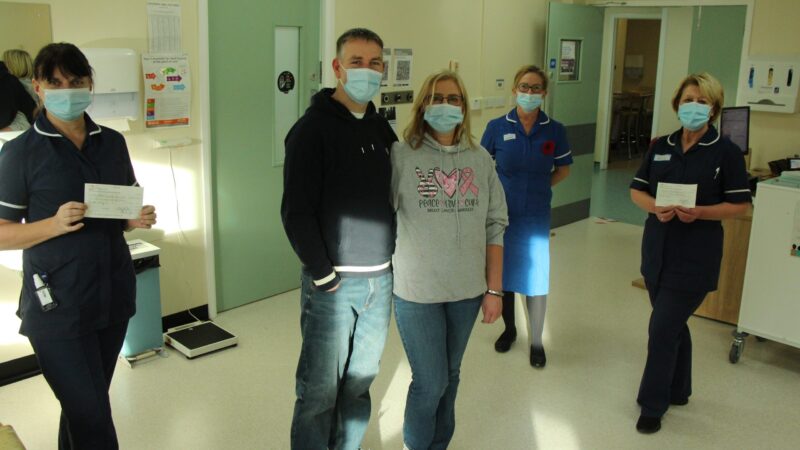 Claire Addison and Bob Menzies on the unit with members of staff. Two staff members hold cheques.