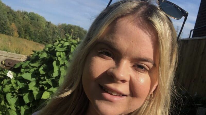 Bethany Cashmore standing outside. She wear sunglasses on her head and is smiling.