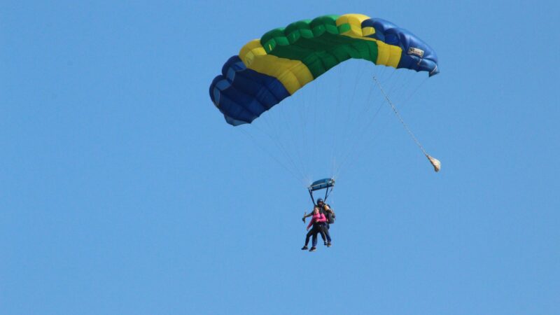 A physiotherapist mid-skydive. She is strapped to a skydiving instructor.