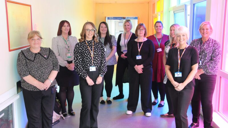 Nine cancer care coordinators stand in a corridor.