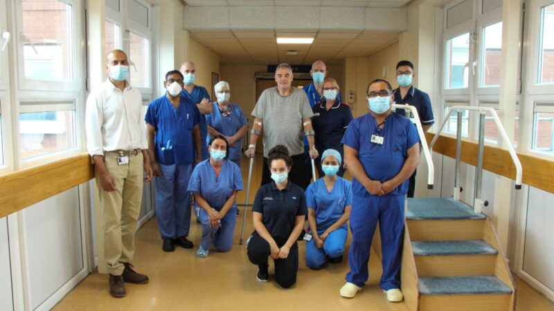 The hip replacement team with Raymond. Raymond stands with crutches.