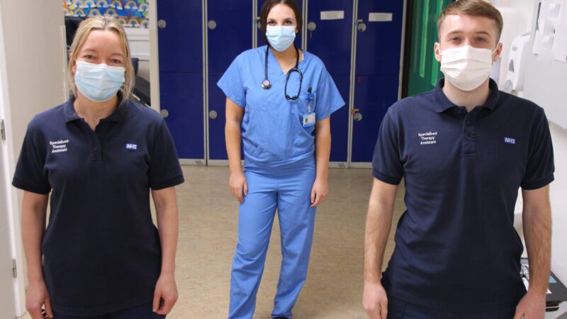 Staff stand in a corridor.