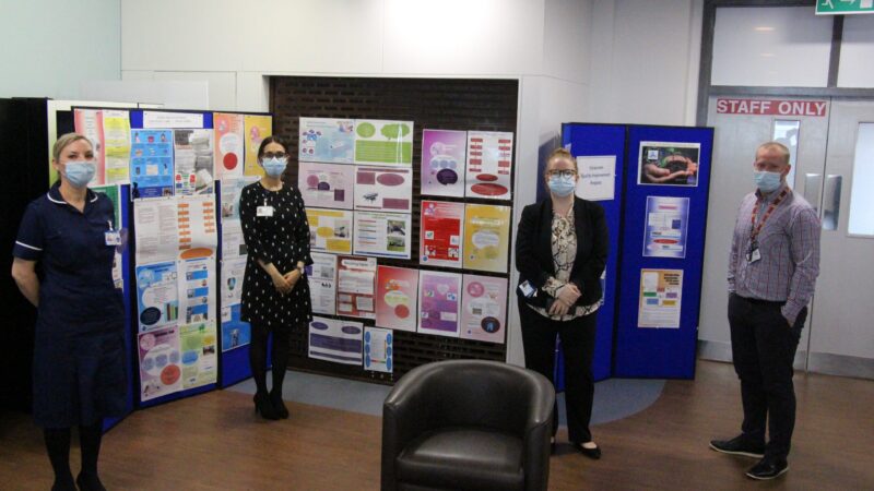 Quality improvement leads stand in front of poster displays.