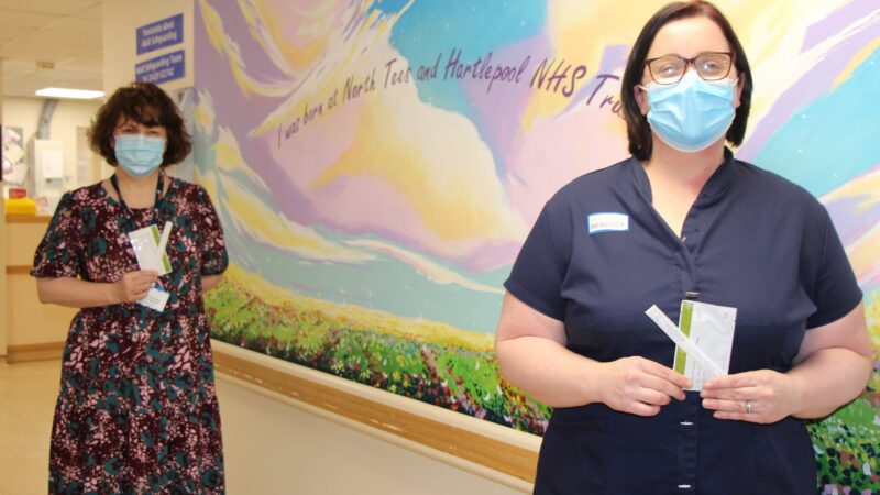 Staff members hold lateral flow tests.