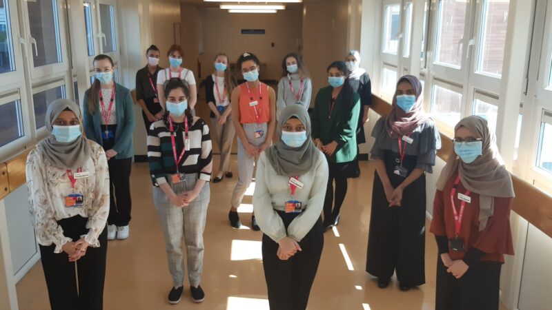 Medical students stand in a corridor.