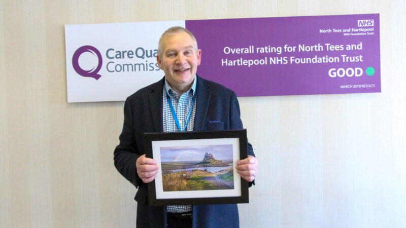 Steve Pett holds a framed photo of a landscape.