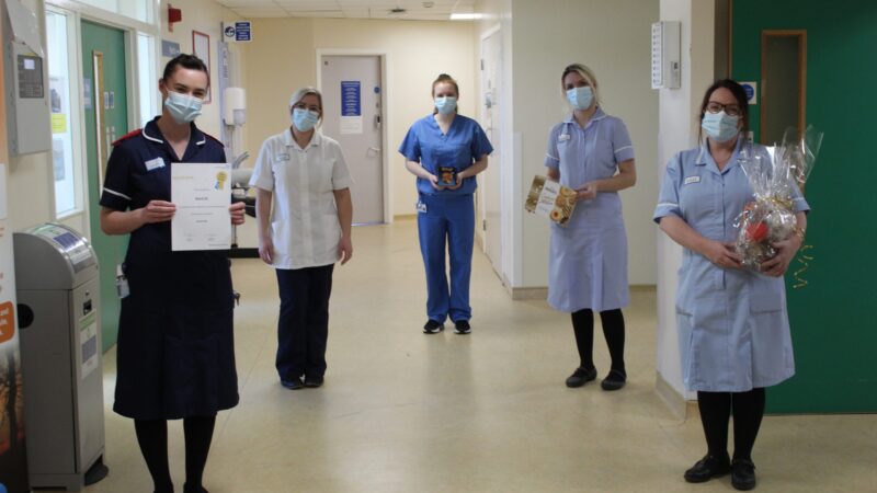 Ward 25 team. One person holds a certificate, another holds a hamper.