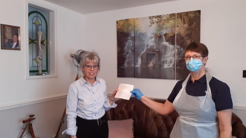 Theresa hands a check to Debra.