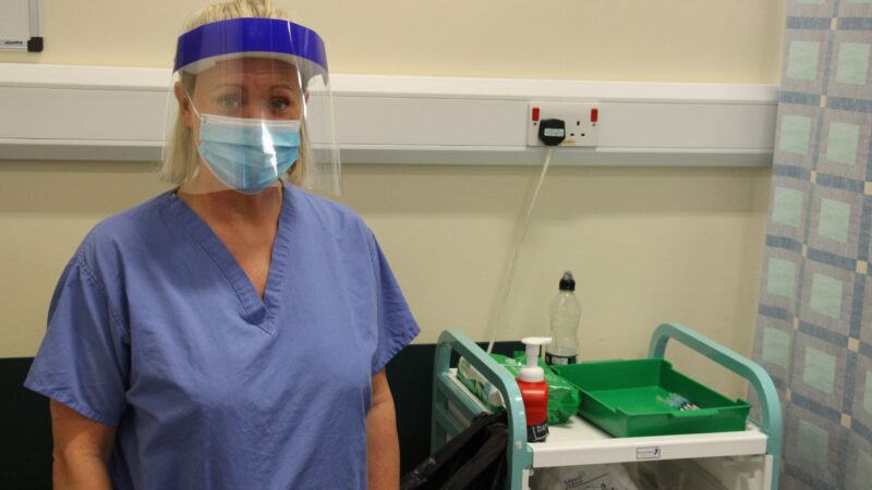 Karen Hampshire with a vaccine trolley. She wears PPE.