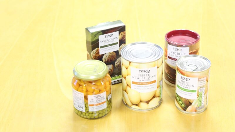 Tins and boxes of food on a table. They include potatoes, peas and stuffing.