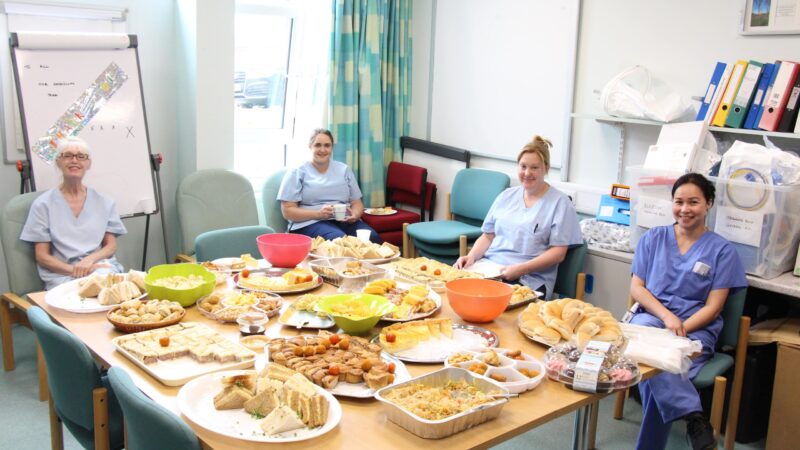 The team sit at a table with a buffet.