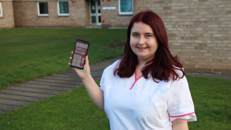 Zoe holds her phone up. Her phone shows a voice banking app.