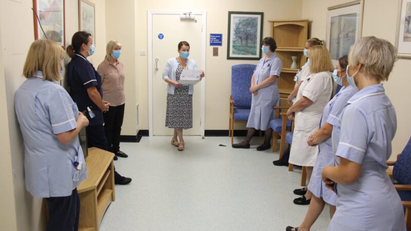 A staff huddle. Someone addresses a group of nurses.